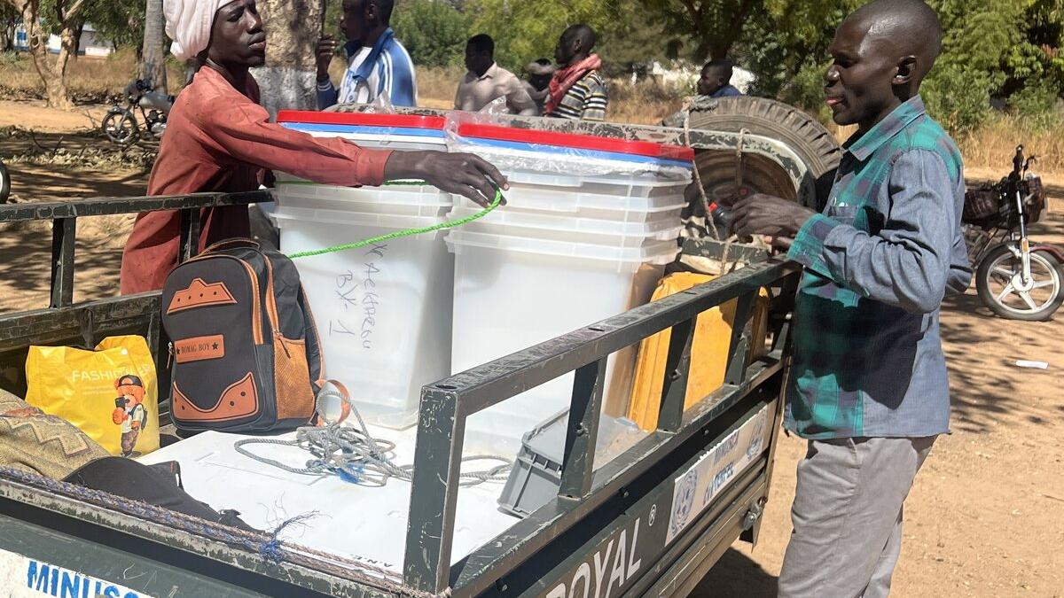 Des personnes attachent des conteneurs de stockage à un véhicule de la MINUSCA.